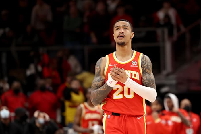 Hawks forward John Collins clasps his hands while walking down the court.